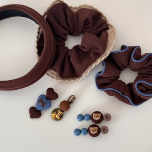 Détail d'un ensemble d'accessoires cheveux marron avec barrettes ours, cœur et chouchous