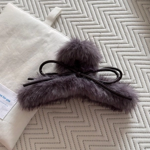 Détail d'une grande pince à cheveux en peluche gris-violet avec nœud en cuir élégant