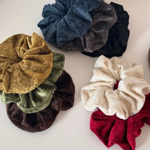Detailed view of eight large chenille velvet scrunchies in various chic autumn colors