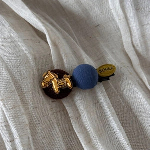 Détail de la pince à cheveux coréenne avec cheval doré et boule de tissu bleue
