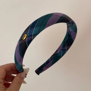 Detail of blue and purple plaid fabric headband with a golden Hand Made metal tag