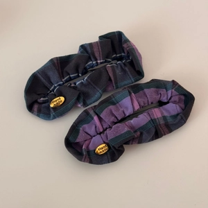 Detail of blue and purple plaid scrunchies featuring handmade gold metal tags