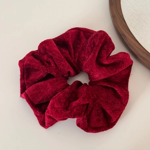 Macro view of a large dark red velvet scrunchie showing plush texture and subtle sheen