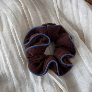 Détail d'un chouchou en tricot marron foncé avec bordure contrastée bleu clair élégante