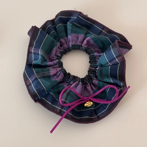 Detail of blue and purple plaid scrunchie with a ribbon bow and handmade metal charm