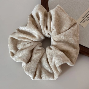 Detailed macro view of beige velvet scrunchie showing plush texture and soft folds