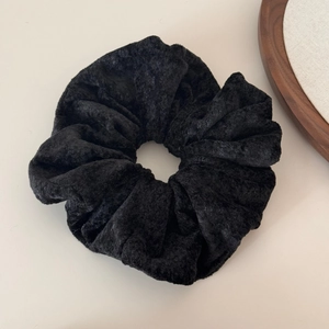 Close-up of black velvet oversized scrunchie showing soft plush fabric and elastic texture