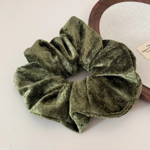 Macro shot of an oversized olive green velvet scrunchie showing soft texture and sheen