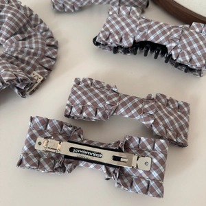 Macro detail of silver metal clip with Seoul Handmade engraving on plaid fabric hair clip
