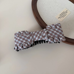 Close-up of brown checkered ruffle bow hair clip with layered fabric and glossy black claw