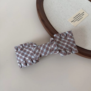Detailed close-up of brown gingham fabric bow hair clip with ruffled pleated edges