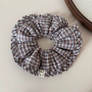 Detail of checkered bow hair clip with handmade label and ruffled fabric texture