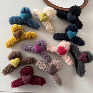 Flat lay of 11 colorful wool felt heart hair claws with soft plush texture in various shades