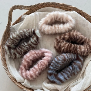Close-up of five assorted plush faux fur scrunchies in animal prints and solid colors