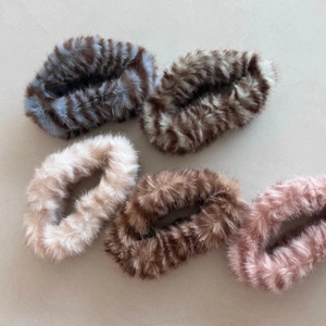 Close-up of five plush faux fur hair scrunchies in soft brown, pink, and white tones