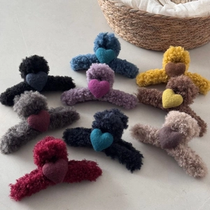 Macro detail of plush heart hair clips in various colors arranged on stone background