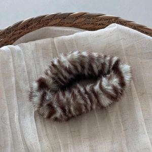 Detail of plush cloud-shaped hair claw clip in brown and white animal faux fur texture