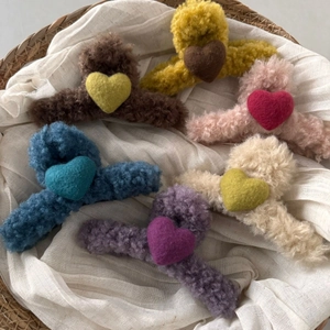 Collection of plush heart hair claws in various colors displayed in a woven basket
