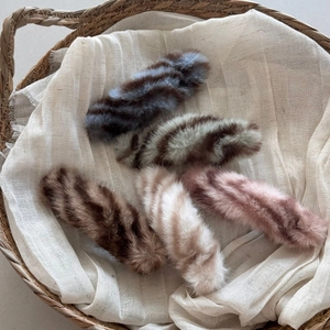 Plush animal print hair clips in five colors displayed in a woven basket with linen liner