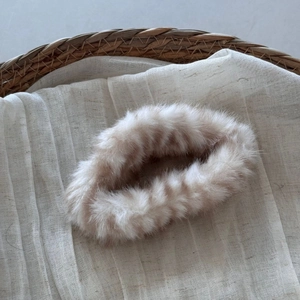 Detail of plush faux fur cloud hair claw with soft beige and brown striped texture