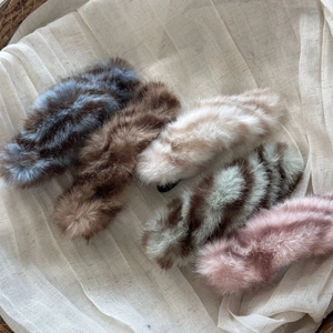 Detail of plush faux fur hair clips in various colors with soft texture and warm finish