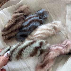 Close-up of five colorful faux fur hair clips on natural linen for autumn styling