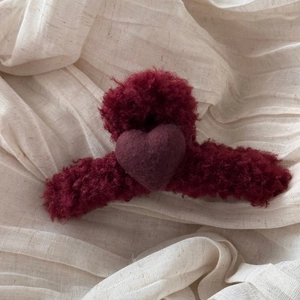Macro shot of a plush dark red heart hair claw clip with wool texture and soft details