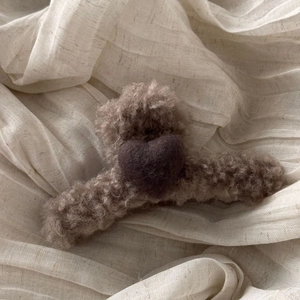 Detail of plush beige shark hair claw clip with dark brown wool felt heart ornament