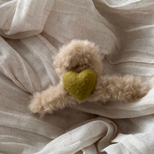 Detail of plush beige shark hair clip with an olive green wool felt heart decoration