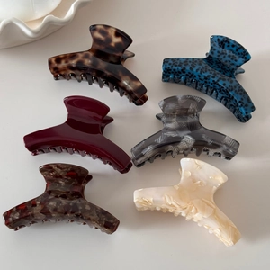 Detailed overhead shot showing six colorful acetate hair claws in various patterns and textures