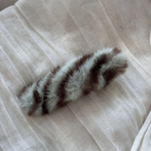 Detail of striped faux fur hair clip with soft texture on light linen background