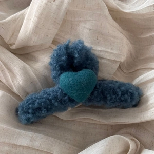 Detail of navy blue plush hair claw clip with a teal wool felt heart on ribbed fabric