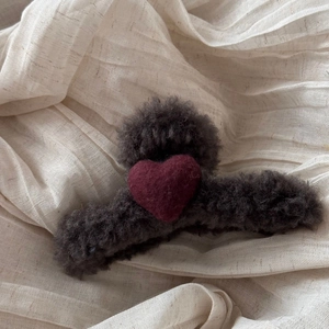Detail of dark grey plush heart hair claw clip with burgundy velvet accent on soft fabric