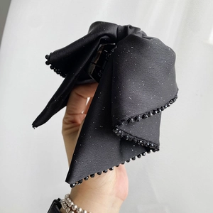 Detail of the black satin bow hair claw with silver glitter and beaded edges