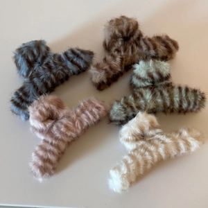 Detailaufnahme von fünf Plüsch-Haarklammern mit Tigermuster in Pastellfarben für Winter