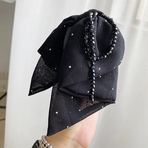 Detail of black chiffon bow hair claw with sparkling beads and sequins texture
