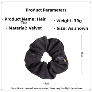 Detail of dark gray velvet scrunchie with brand tag and soft pleated texture