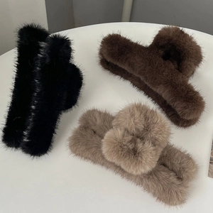 Vue détaillée de trois grandes pinces à cheveux en peluche de couleur noir, marron et café