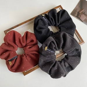 Detail of fabric scrunchies with white polka dots and gold Lucky charms in three colors