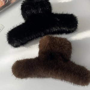 Détail de grandes pinces à cheveux en fausse fourrure noire et marron avec ressort métal
