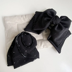 Detail of black silk bow hair claw with shimmering silver glitters and beaded edges