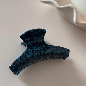 Detail of the dark blue acetate hair claw with leopard pattern on a minimalist tray