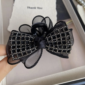 Détail de la pince à cheveux élégante avec nœud en résille noire et strass brillants en gros plan