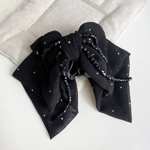 Detail of black fabric bow hair claw clip with beaded tassels and silver sequins