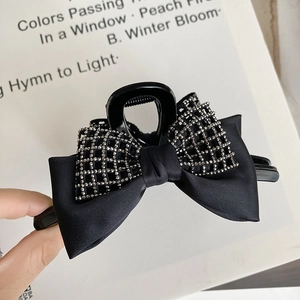 Detail of a large black bow hair claw clip with silver rhinestones on satin fabric