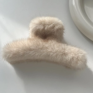 Détail d'une pince à cheveux en peluche beige, texture douce pour coiffure d'hiver