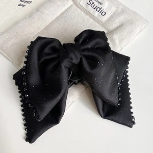 Macro shot of large black bow hair claw clip with silver glitter and beaded trim detailing