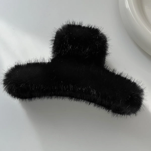 Gros plan d'une grande pince à cheveux en peluche noire avec texture en fausse fourrure
