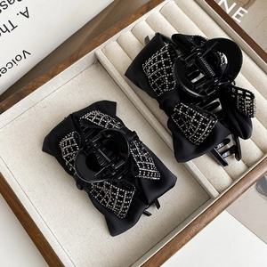 Detail of elegant black satin bow hair claws with silver rhinestone mesh on a jewelry tray