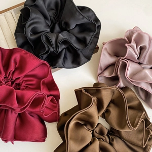 Detailed view of four-layer satin hair scrunchies in black, burgundy, pink and brown
